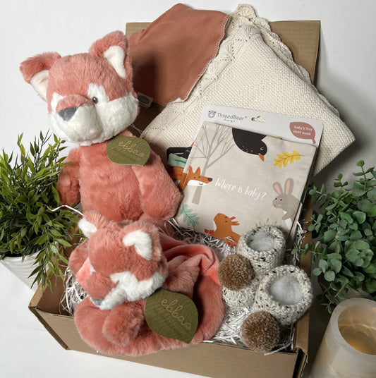 Ebba Fox eco friendly new baby hamper containing acotton baby blanket, a cloth baby book, hand crocheted baby booties, a cotton dribble bib and two Ebba fox soft baby toys.