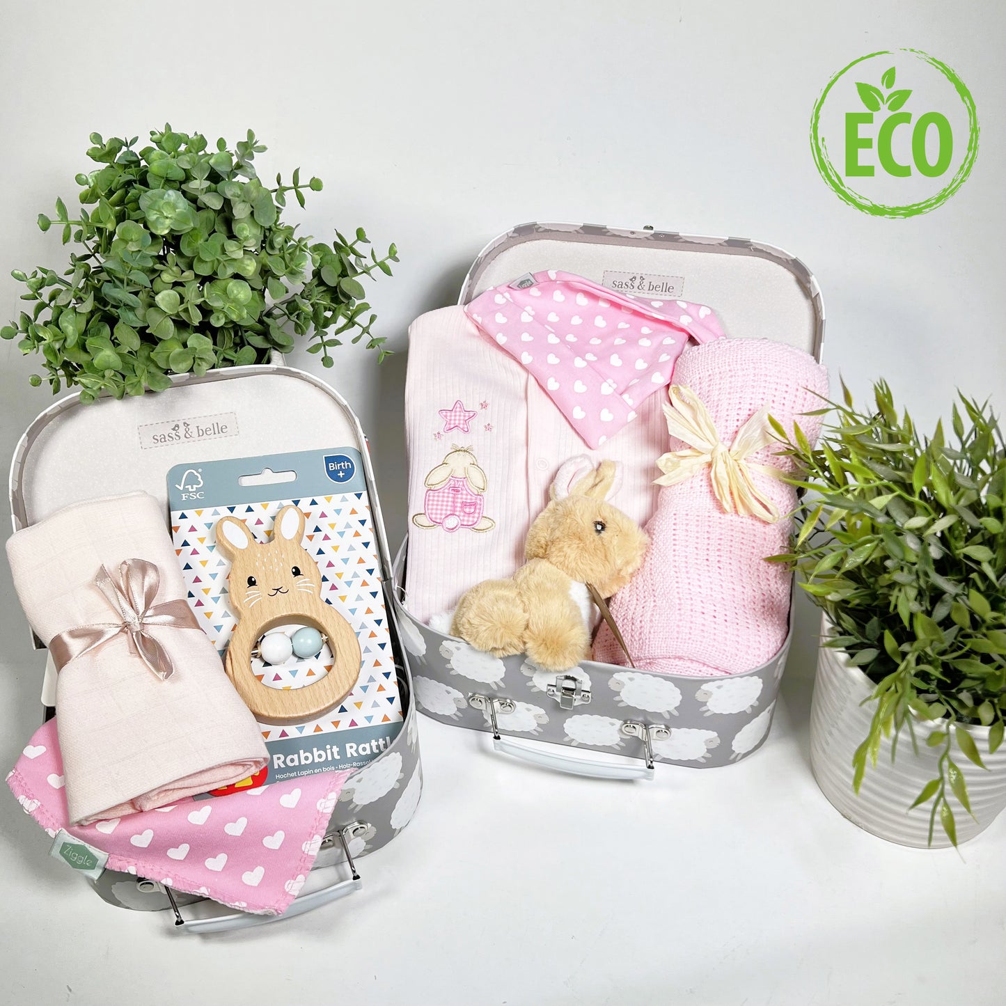 Eco Friendly pink and white baby girl gift contains a pink cotton ribbed baby sleepsuit wit an applique rabbit looking at a star, a pink cotton cellular baby blanket,a FSC wooden bunny shaped baby rattle, an eco friendly bunny soft toy, a coton baby bib and matching baby knot hat and 2 baby keepsake cases.