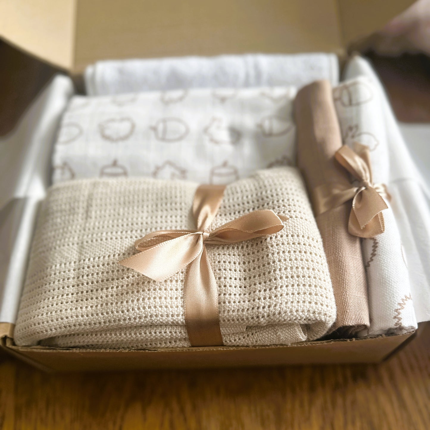 neutral baby hamper with cellular baby blanket, muslins, swaddle, and hooded baby towel.