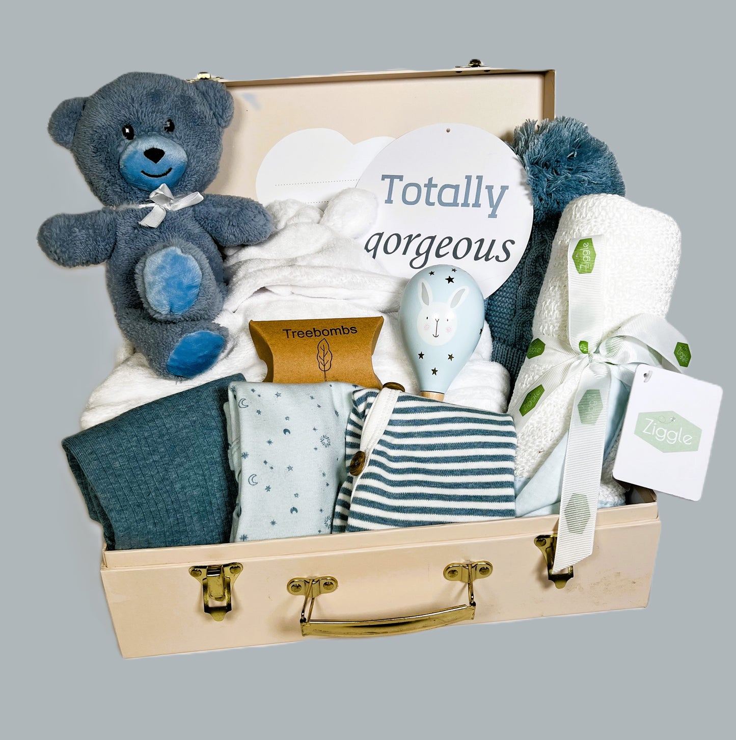Blue new baby boy hamper in a cream baby keepsake case with a set of blue baby bodysuits, a white cotton cellular baby blanket, a baby rattle, baby hat with pompom and a white baby dressing gown.
