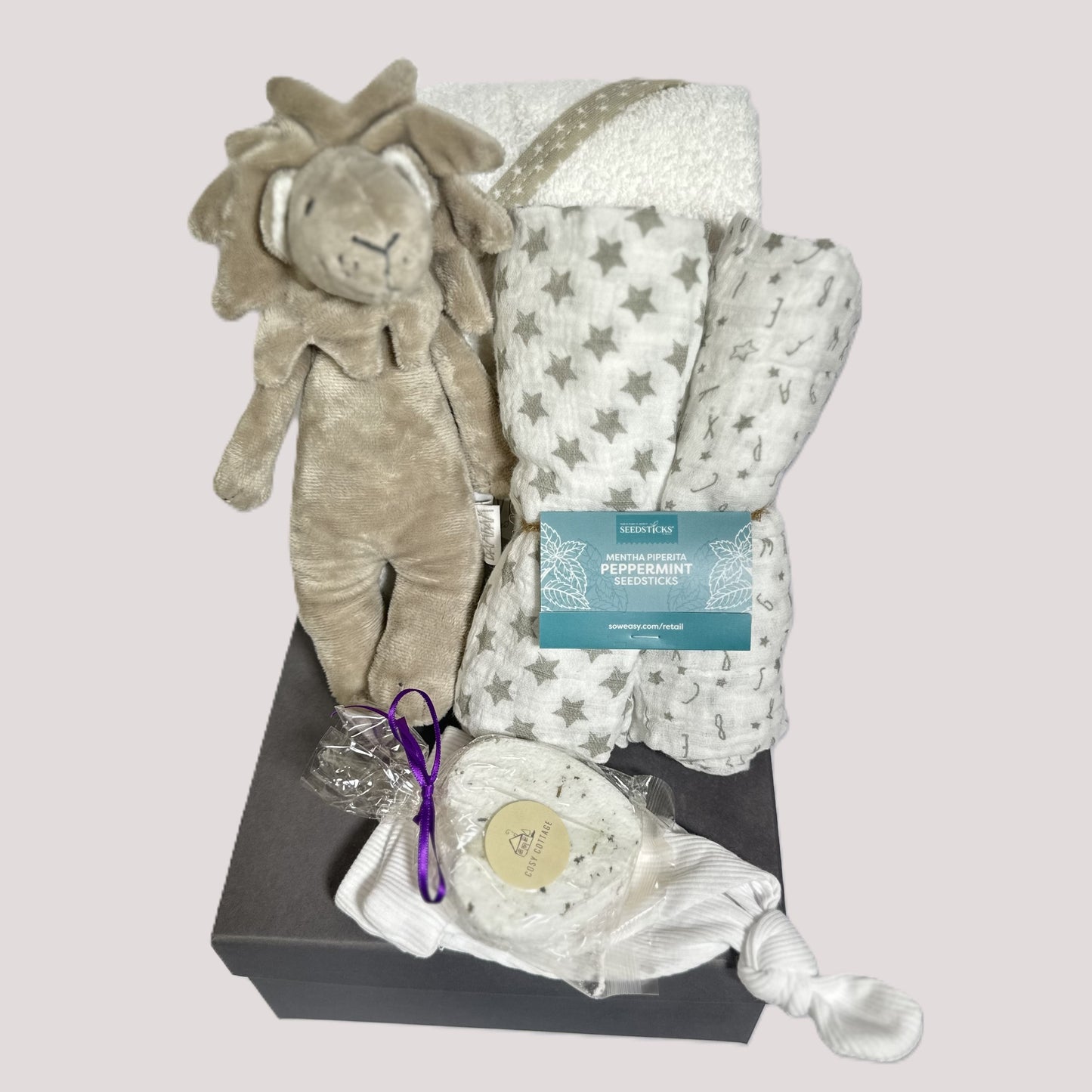 A neutral baby hamper with a lion baby rattle, hooded baby towel, baby muslins, a baby knotty hat and a lavender bath bomb.
