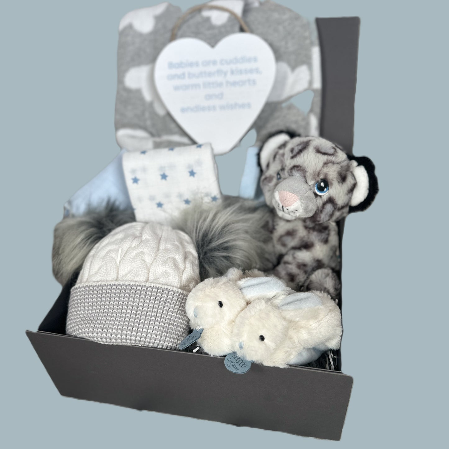 Baby boy hamper with soft toys and baby items in a box on a light blue background