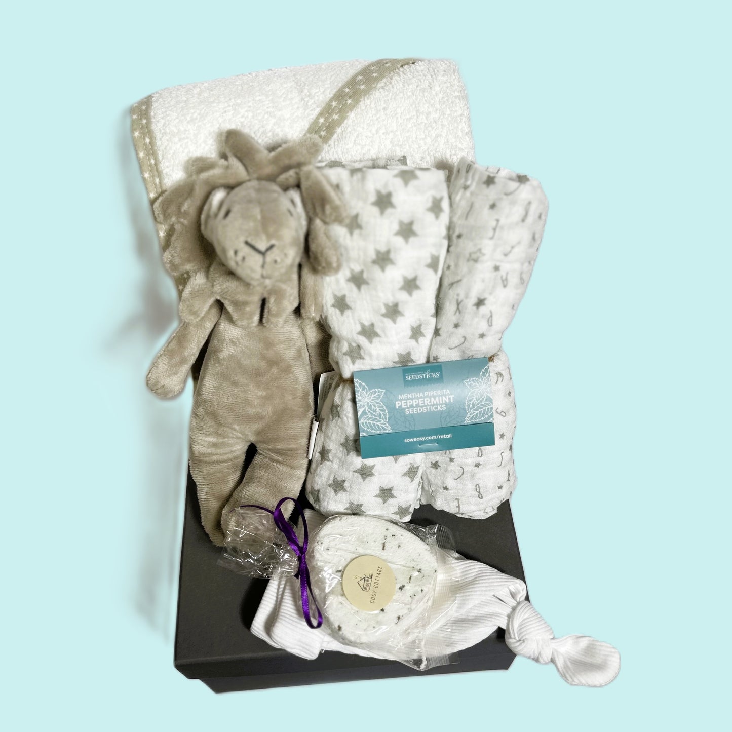 A neutral baby hamper with a lion baby rattle, hooded baby towel, baby muslins, a baby knotty hat and a lavender bath bomb.
