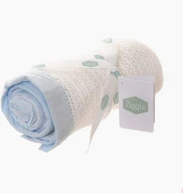 A white cotton cellular baby blanket with a light blue cotton trim all around.