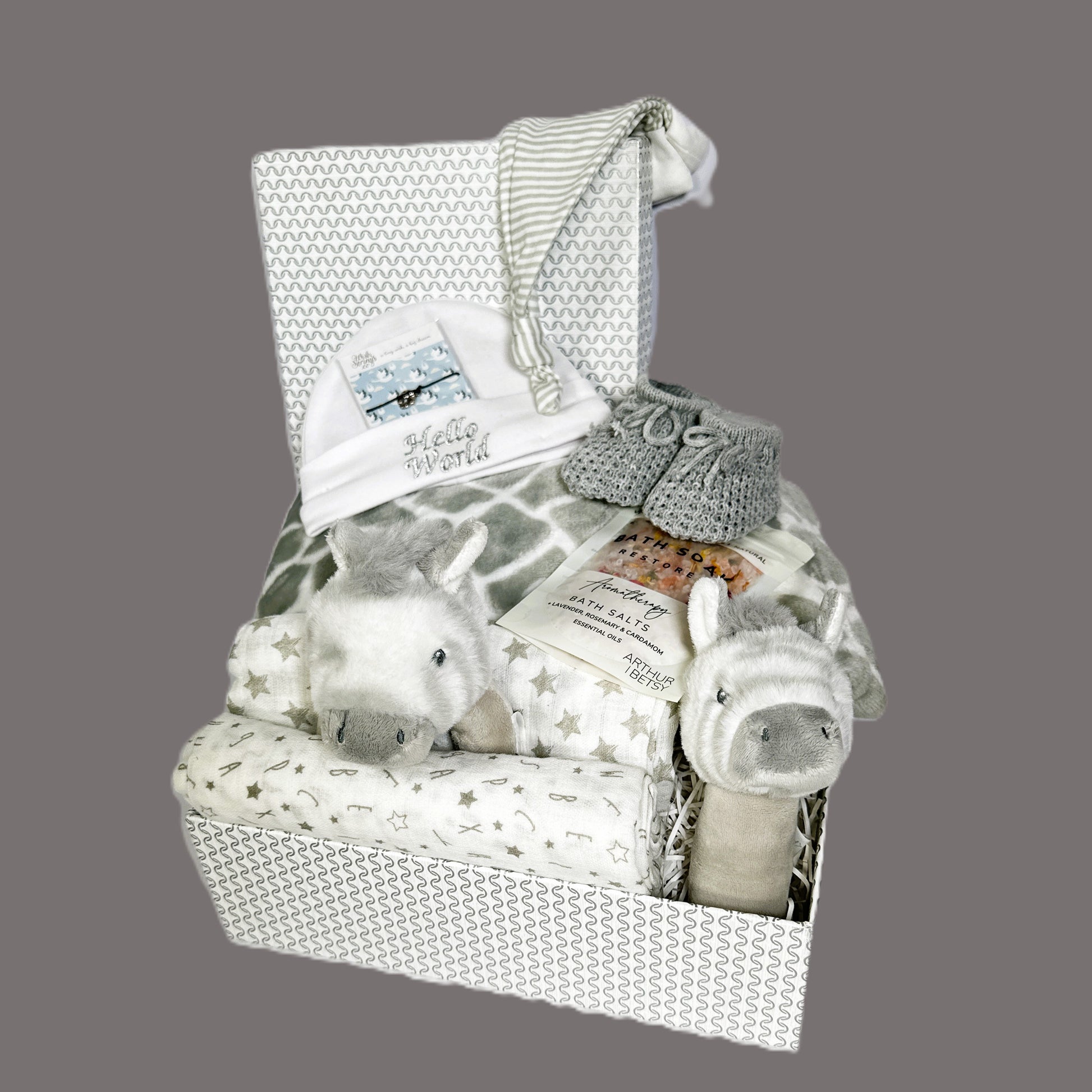 This zebra themed baby hamper comes in a grey and white  baby keepsake box and contains 2 soft zebra baby rattles, a grey baby blanket with a grey and white giraffe pattern, a pair of grey baby booties, a wish bracelet, a baby grey knot hat and a white cotton baby hat along with 2 baby muslin squares.