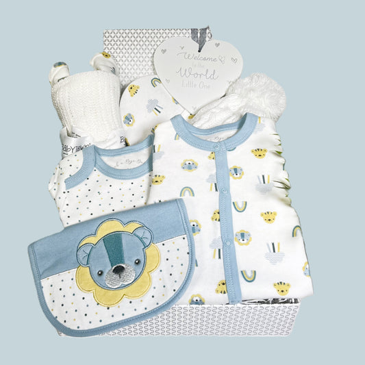A new baby boy baby shower gift in a silver  and white baby keepsake box containing a cotton layette set with blue and yello lion print, a white cotton cellular baby blanket, a baby pompom hat and a grey and white heart shaped nursery sign.