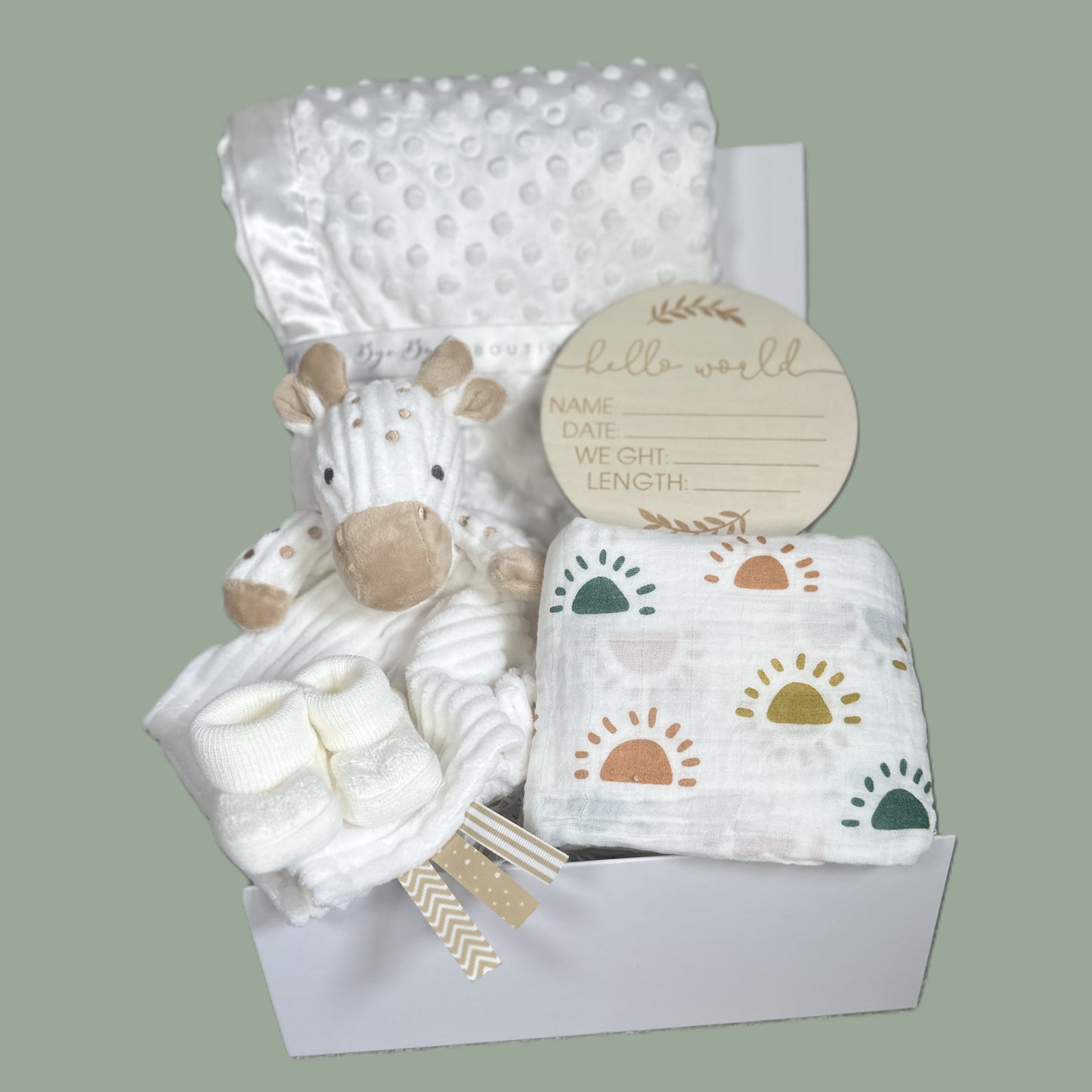 Baby gift set with giraffe comforter, white baby blanket, and birth announcement plaque on a light green background
