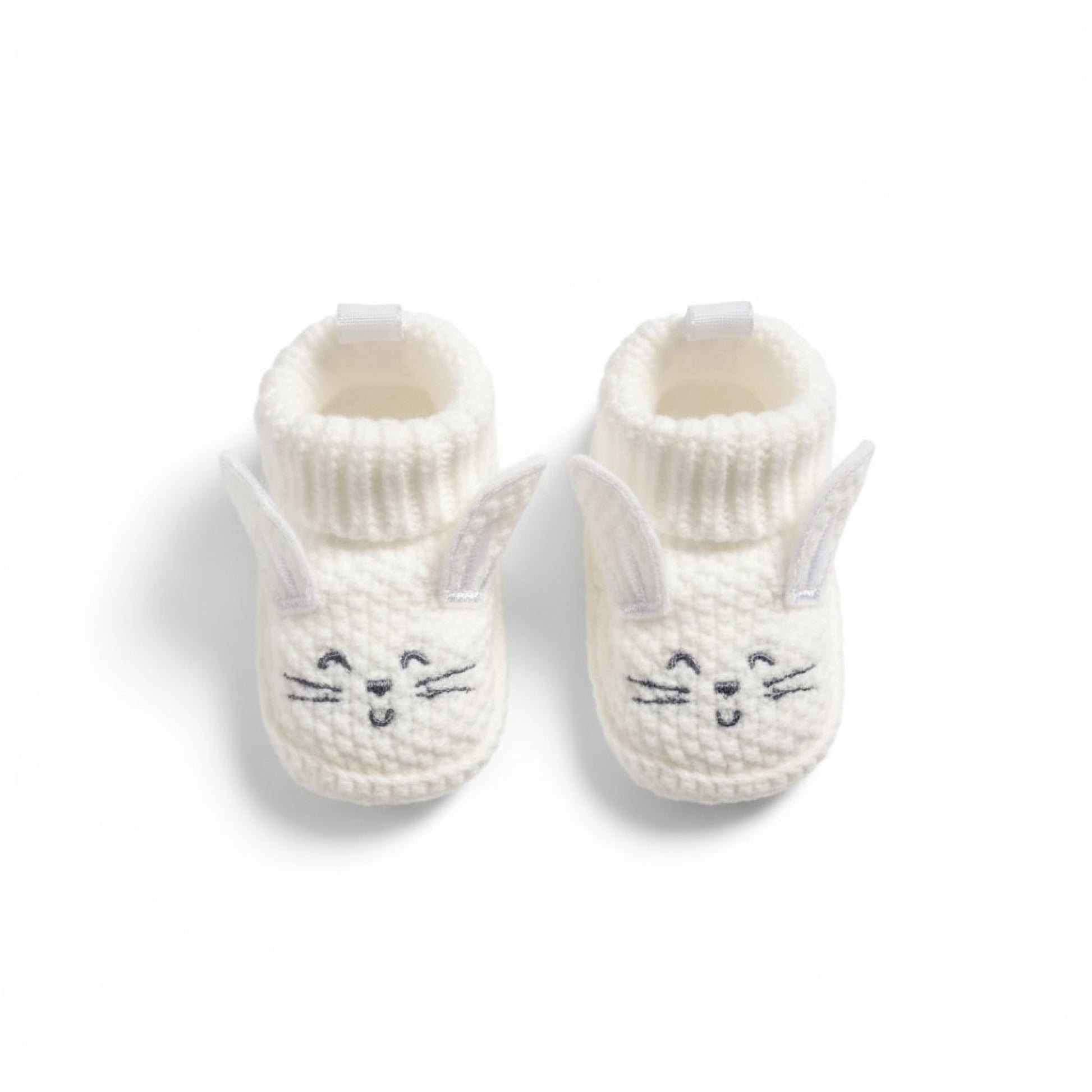 Pair of white knit baby booties with bunny face design on a white background