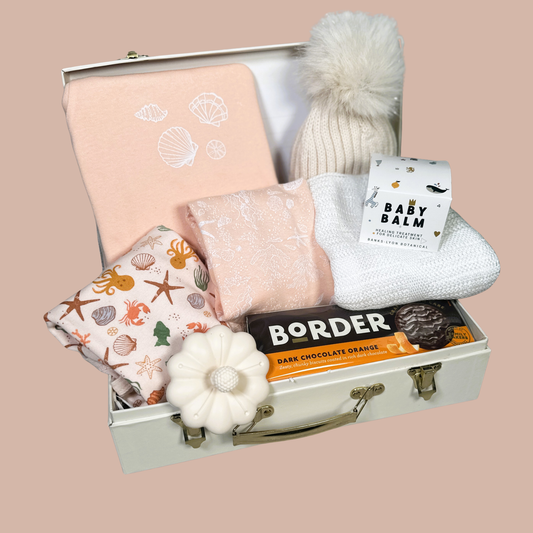 Paech babywear in a baby hamper case with tether, chocolate biscuits, baby pompom hat. white cellular baby blanket and taupe baby pompom hat