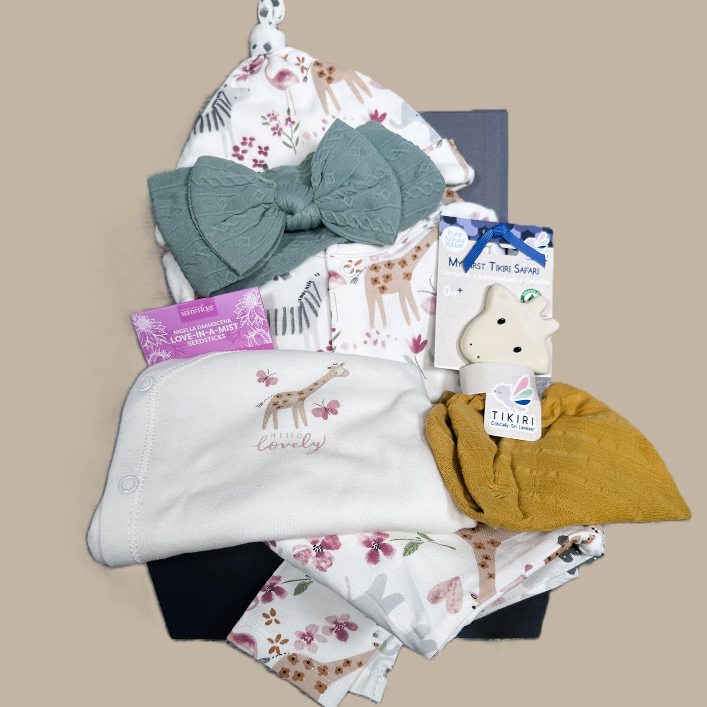 New baby girl hamper with cotton baby sleepsuit, giraffe baby teether and green baby headband.