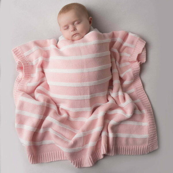 baby sleeping under a pink and white striped cotton baby blanket.