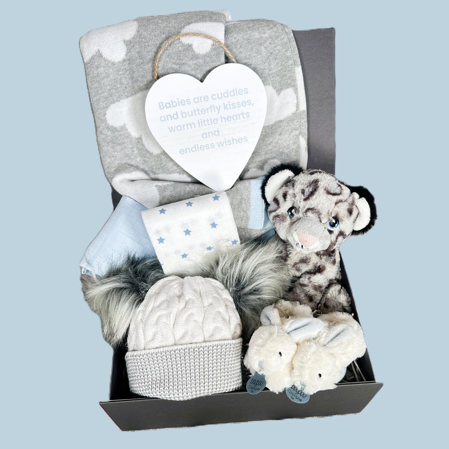 Baby gift set with plush toys, hat, and blanket on a light blue background