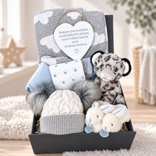 blue and grey baby boy hamper with blue white and grey baby blanket, Keel snow leopard soft baby toy, a pair of doudou bunny baby slippers and white double pom pom baby hat  and two muslin squares in a baby keepsake box