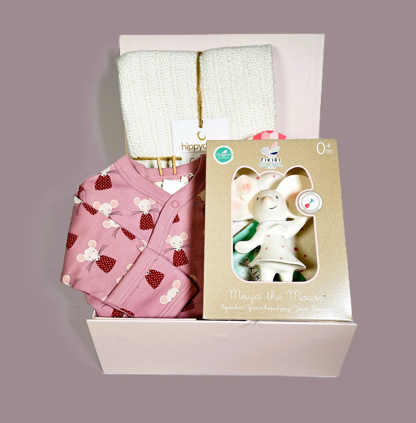 A new baby girl hamper in a magnetic baby keepsake case containing an organic baby romper with lovely mouse print, a Tikiri natural rubber teething toy and a white Hippychick cotton cellular baby blanket.