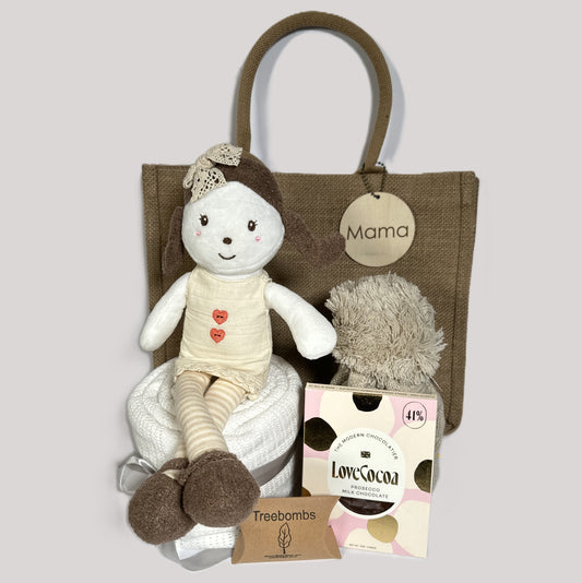 Emily rag doll new baby hamper in a hessian "Mama" bag with a white baby blanket, a bar of chocolate and a baby pompom hat.