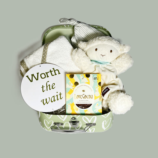 Baby shower gifts in a baby keepsake case containing a Kallo Vanilla lamb baby comforter which is also a puppet. A cotton hooded baby towel, a striped n cotton baby knotty hr and a bar of Love Cocoa "Bunnycomb" milk chocolate