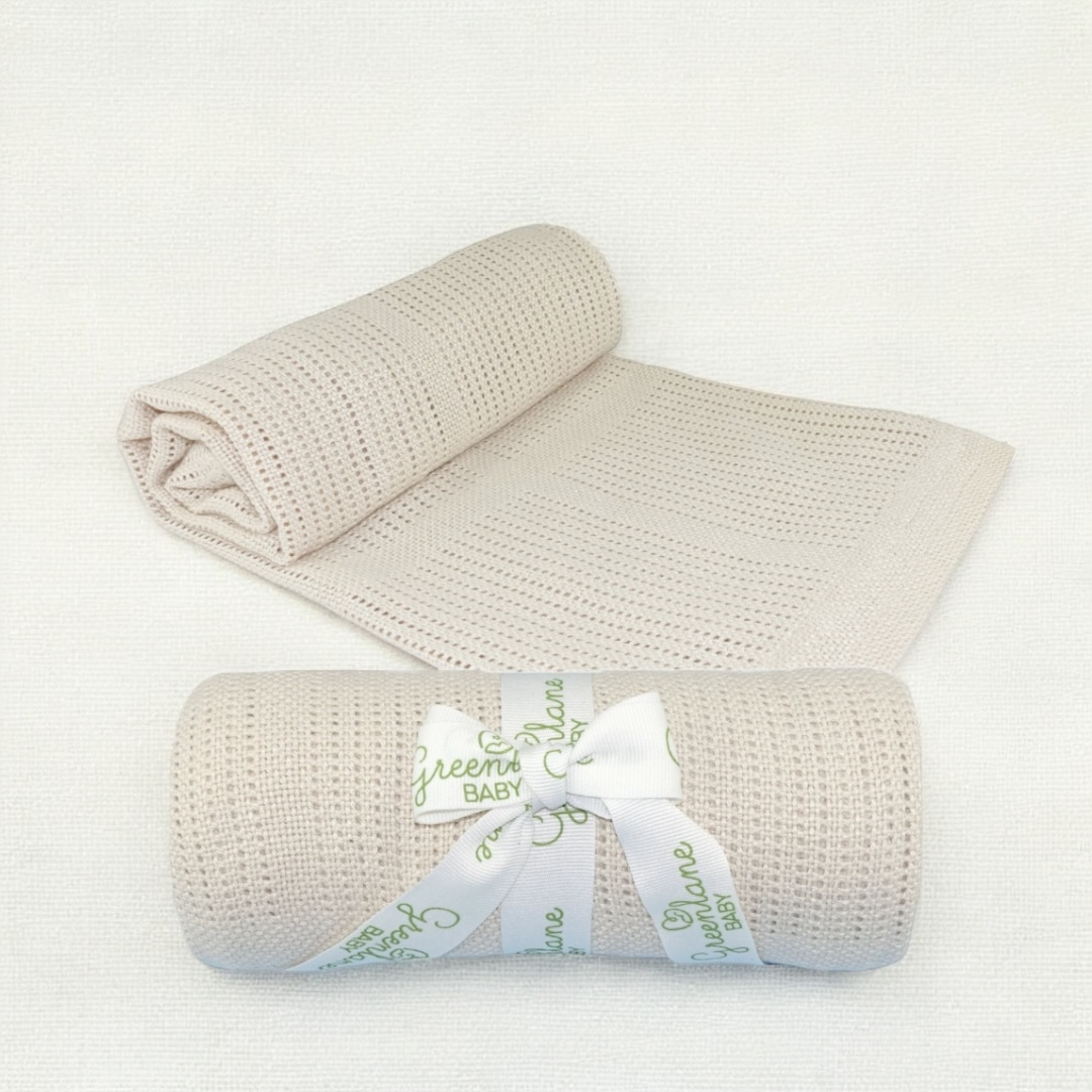 Beige knitted cellular baby blanket with a white ribbon and 'Green Baby' label on a white background