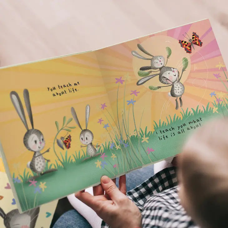 Illustrated book open to a page with bunnies and butterflies on a colorful background