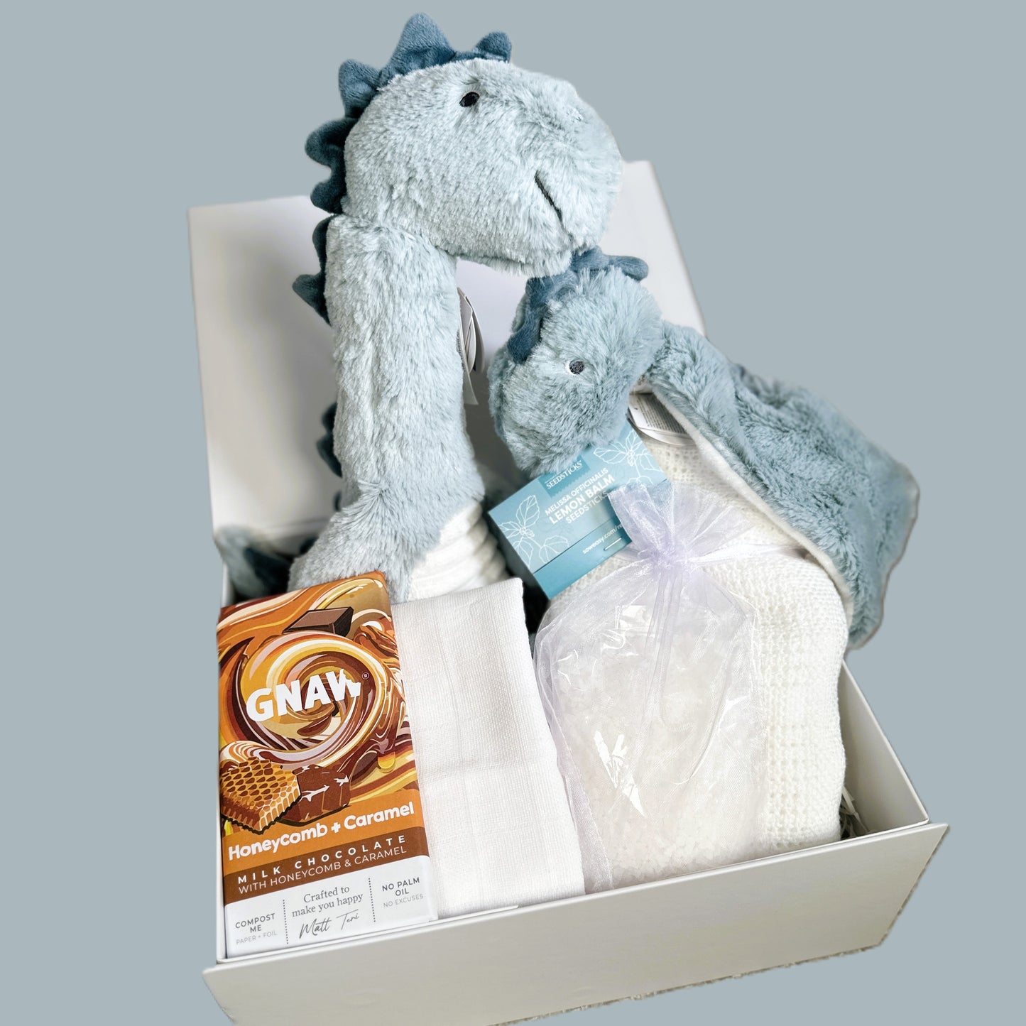 Baby hamper with light blue dinosaur soft baby toy and baby comforter