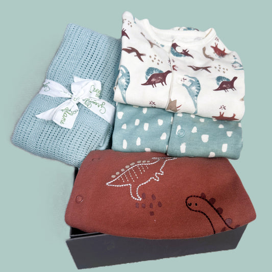 Dinosaur new baby boy hamper with dinosaur themed baby sleep suit and a sage green bamboo and cotton baby blanket in a baby keepsake box.