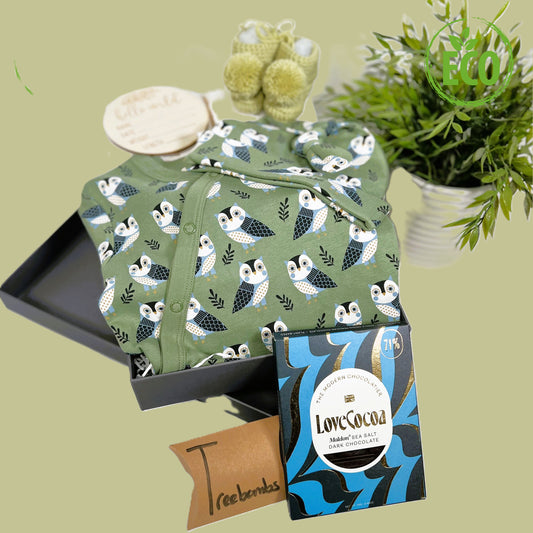 Organic cotton baby romper in green with blue and white owl print, matching baby knot hat, merino wool baby booties with pompom, white cotton cellular baby blanket, baby "Hello world" disc, a bar of Love Cocoa chocolate and baby keepsake box.