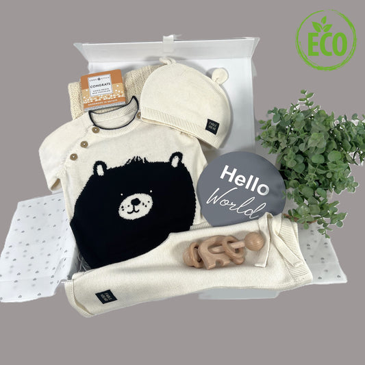 Stunning neutral new baby gift hamper containing organic cotton baby clothing set, wooded baby rttle, cotton cellular baby blanket and contained in a white magnetic baby keepsake box.