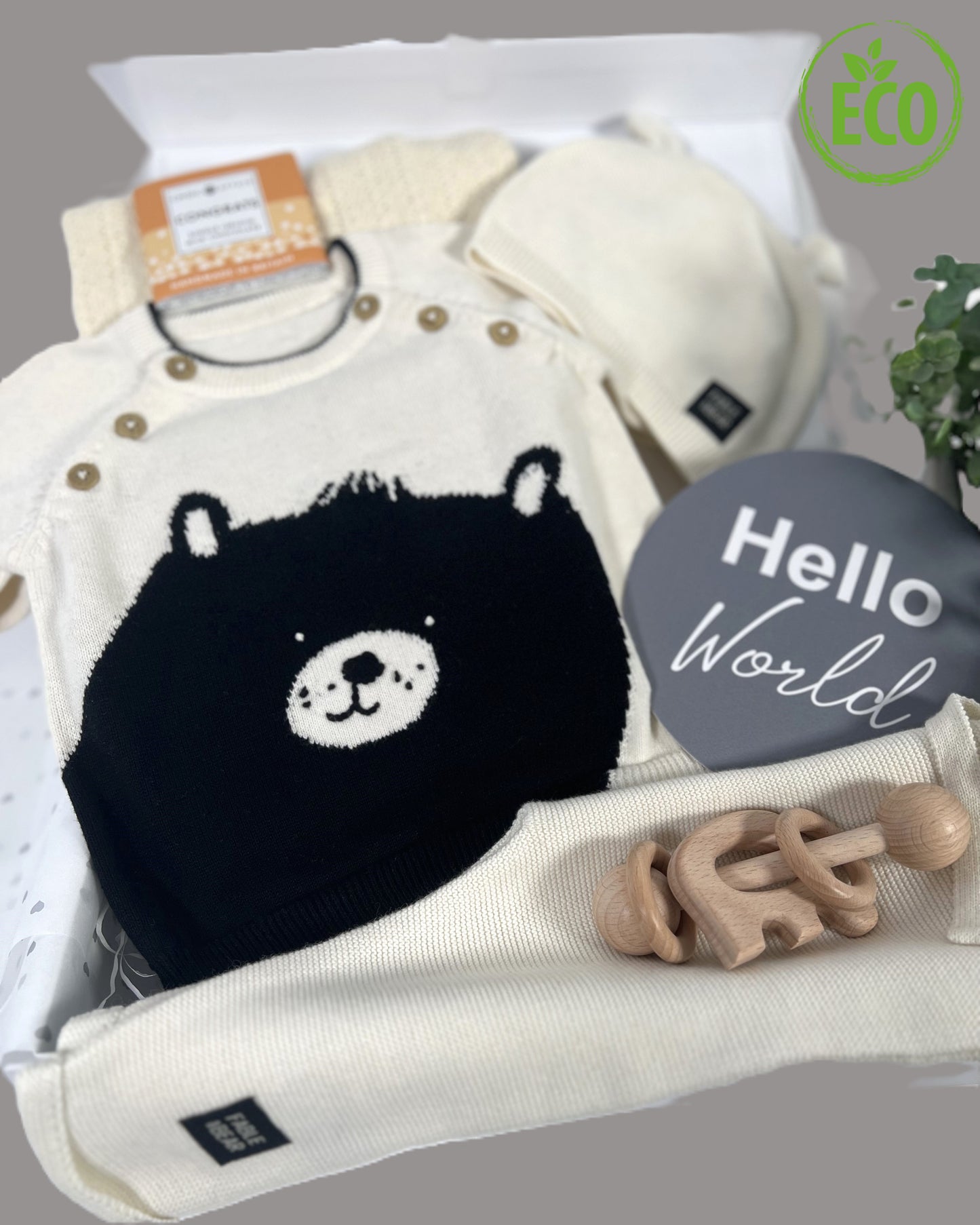 Stunning neutral new baby gift hamper containing organic cotton baby clothing set, wooded baby rttle, cotton cellular baby blanket and contained in a white magnetic baby keepsake box.