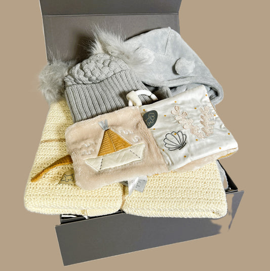 A baby hamper gift in a grey baby keepsake box containing a almond Hippychick cellular cotton baby blanket, a Nattou Charlie baby sensory book, a grey baby dressing gown and a baby pompom hat.