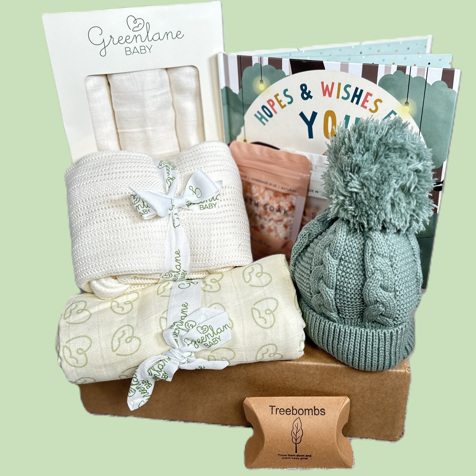 Baby gift set with blankets, a hat, and a BABY BOOK on a light green background