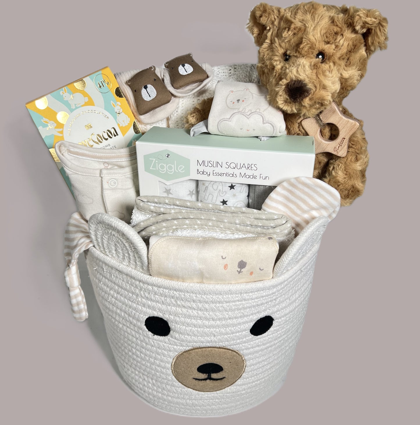 Baby Hamper gift in a rope bear storage caddy containing a |Eco freindly bear soft toy, a cottone baby leyyette set, a hooded baby towel, a white cotton cellular baby blanket and treats for the new mummy.