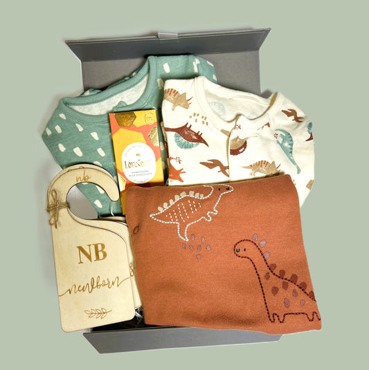 Baby boy hamper in a grey magnetic baby keepsake box containing a set of three dinosaur pint baby body suits in cotton, a lovely little bar of Love cocoa chocolate and a set of wooden baby wardrobe dividers.