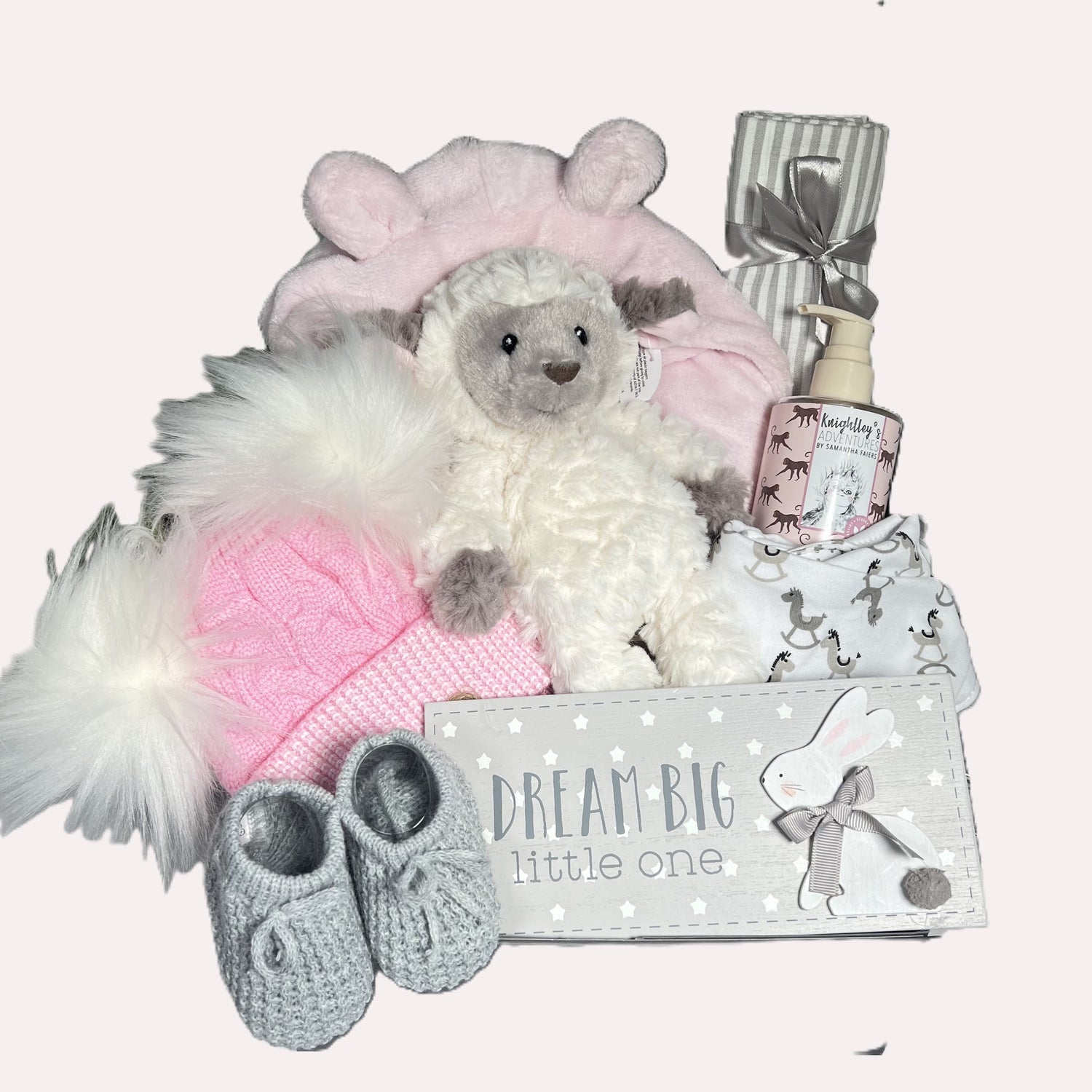 Pink new baby girl gift includes a pink baby dressing gown , a Mary Meyer Lamb soft baby toy, a bottle of baby wash, a grey and white muslin square. apink and white baby pompom hat, a pair of grey baby booties, a baby dribble bib, a nursery plaque 