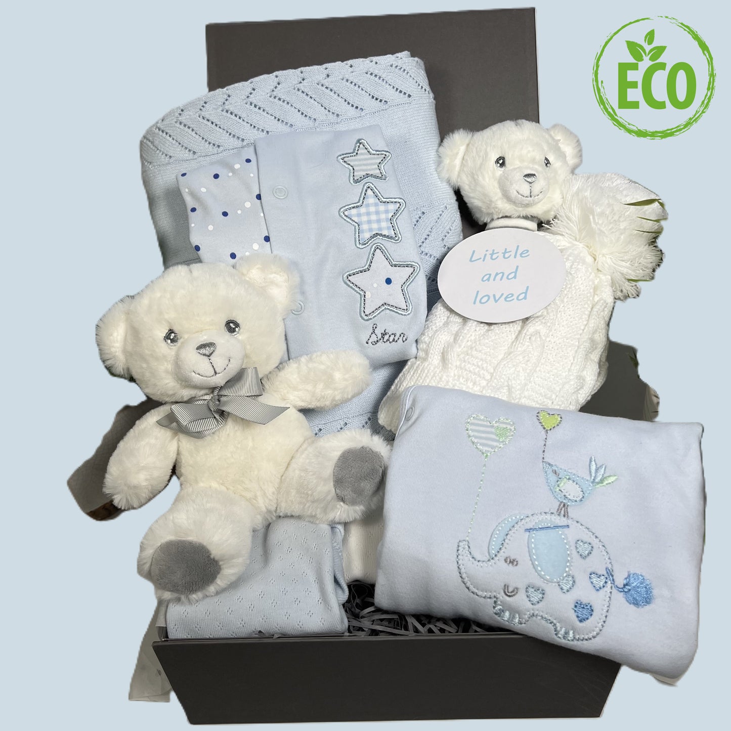 Blue new baby boy gift containing a cotton blue baby blanket, 2 blue cotton sleepsuits with embroidery, a Keeleco 14cms white teddy bear and a Keeleco with baby rattle, a white pompom baby hat, a blue cotton baby bodysuit, a photography plaque and baby keepsake box.