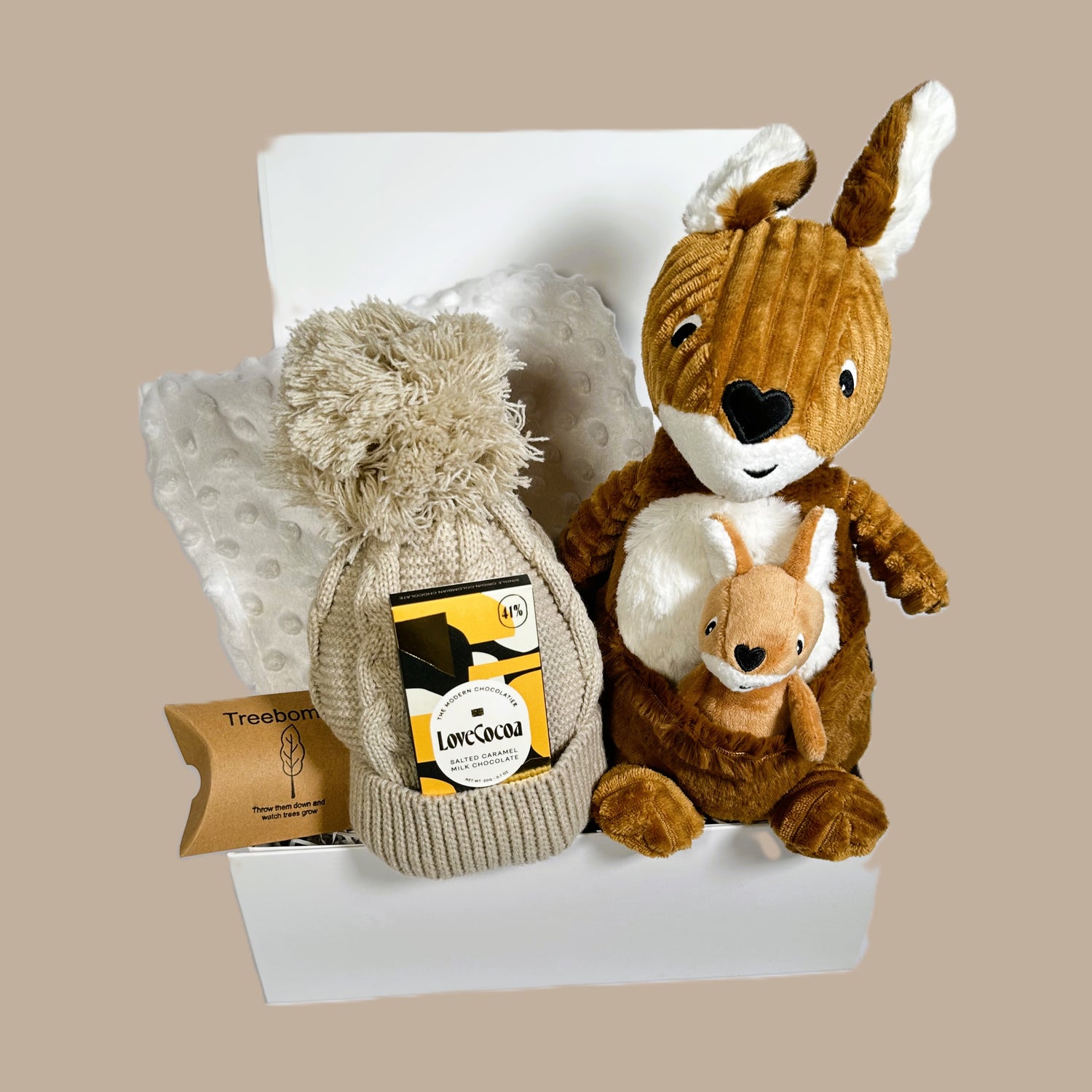 Baby hamper with a kangaroo soft baby toy and her baby, a white bubble baby blanket, a biscuit coloured baby pompom hat, a mini bar of Love Cocoa salted caramel chocolate and a white baby keepsake box.