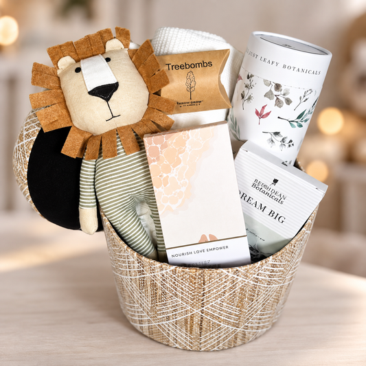 A new baby hamper in a seagrass storage box with a Caron the lion soft baby toy, a white cotton cellular baby blanket, a large bamboo baby swaddle blanket/muslin, a bar of organic baby soap , a solid oil bath soap bar and 3 Treebombs.