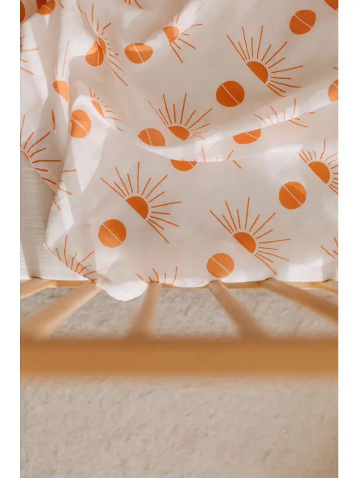 Large white muslin swaddle blanket with orange sunshine print.