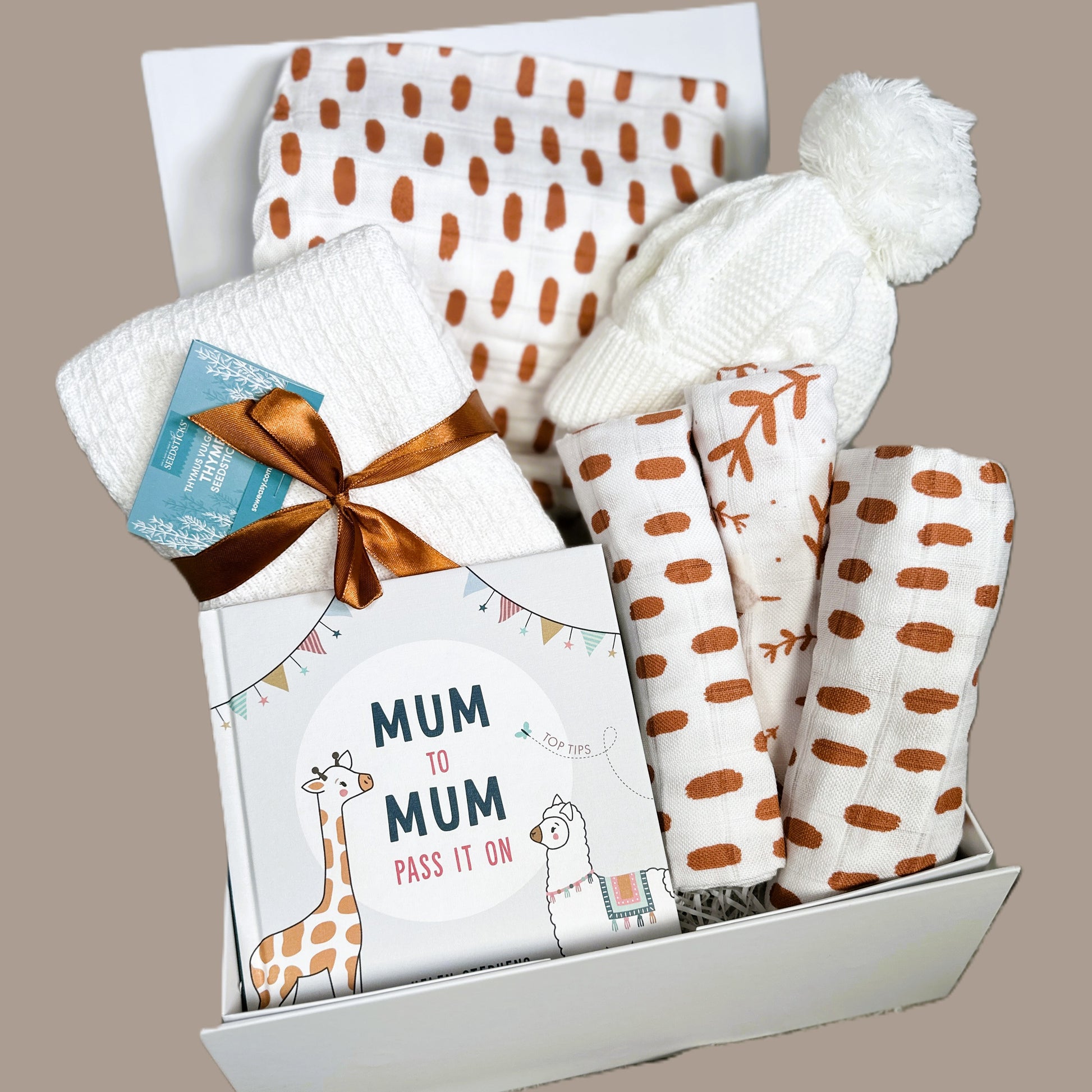 Gift set for new mums with baby swaddle blanket, muslins hat, baby blanket and a book.