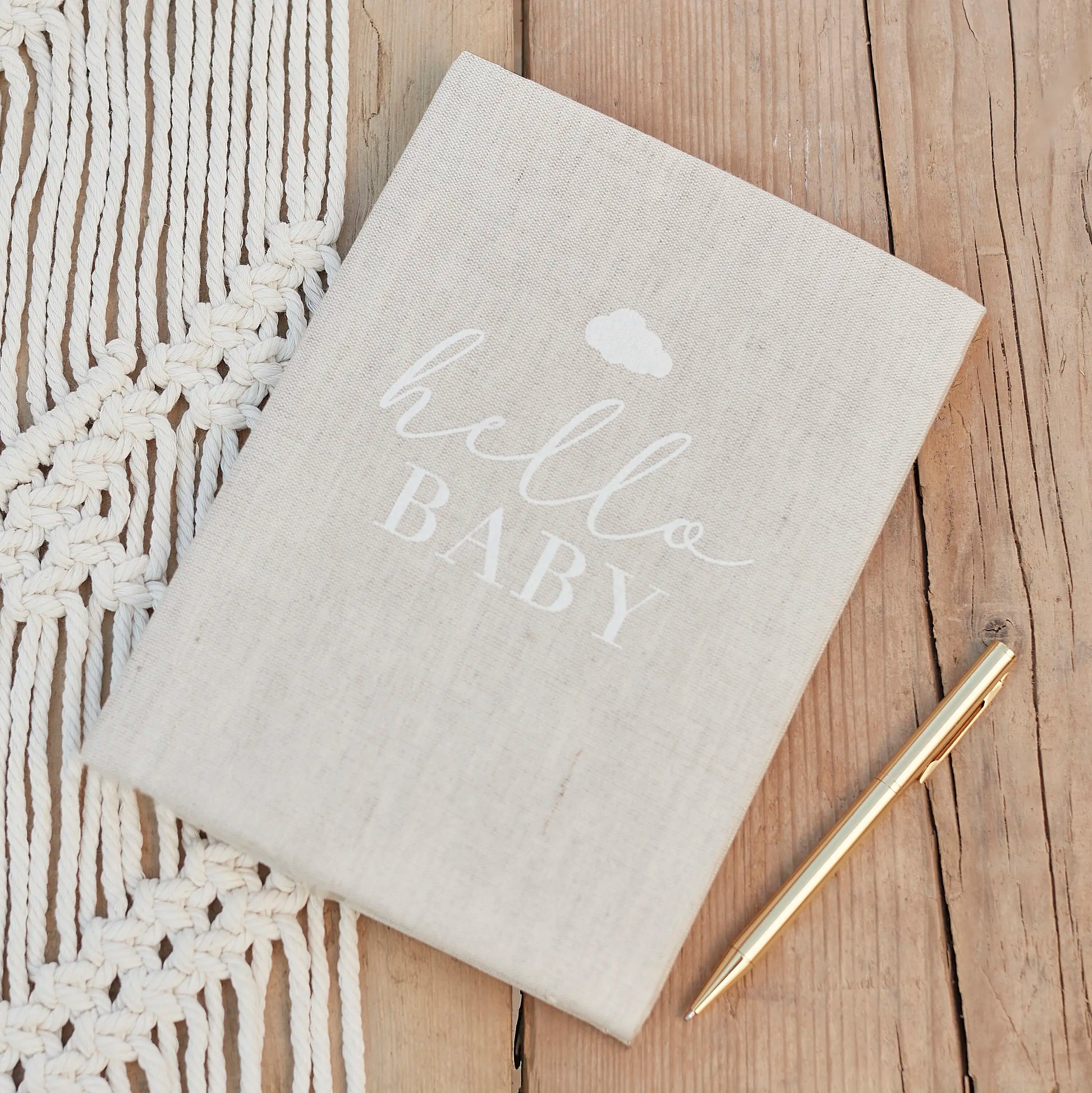 Notebook with 'hello BABY' text on a wooden surface with a gold pen.