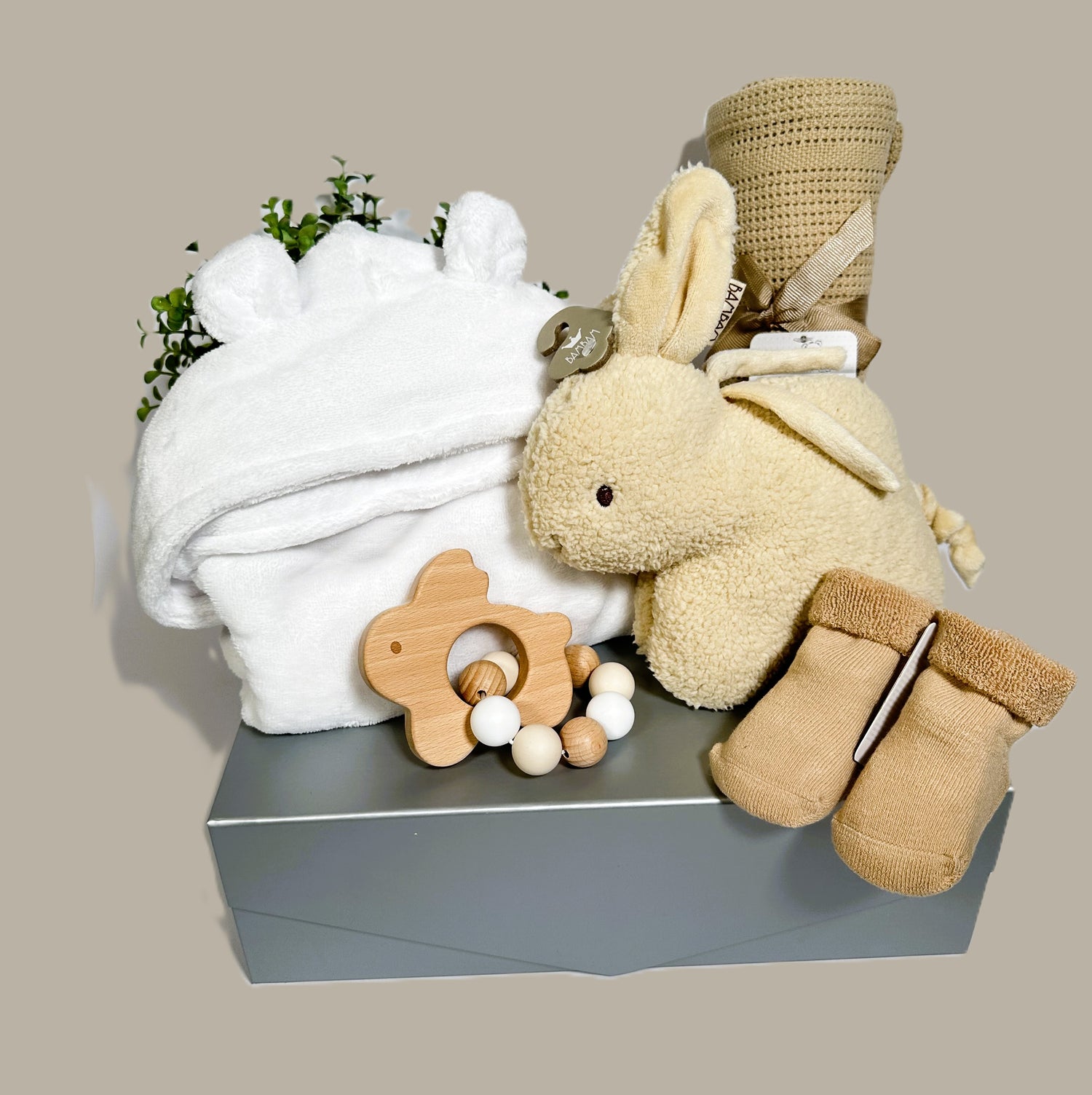 A Beautiful new baby hamper with a Bambam musical Bunny, a pair of baby socks, a baby dressing gown, cellular baby blanket and a bunny wood and  a silicone teething ring.