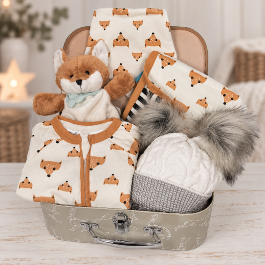 Baby hamper containing a cotton fox print zipped baby sleepsuit and matching dribble bib. A fox print baby blanket. A Kaloo fox baby comforter and puppet. A grey and white baby pompom hat in a sage green baby keepsake case.