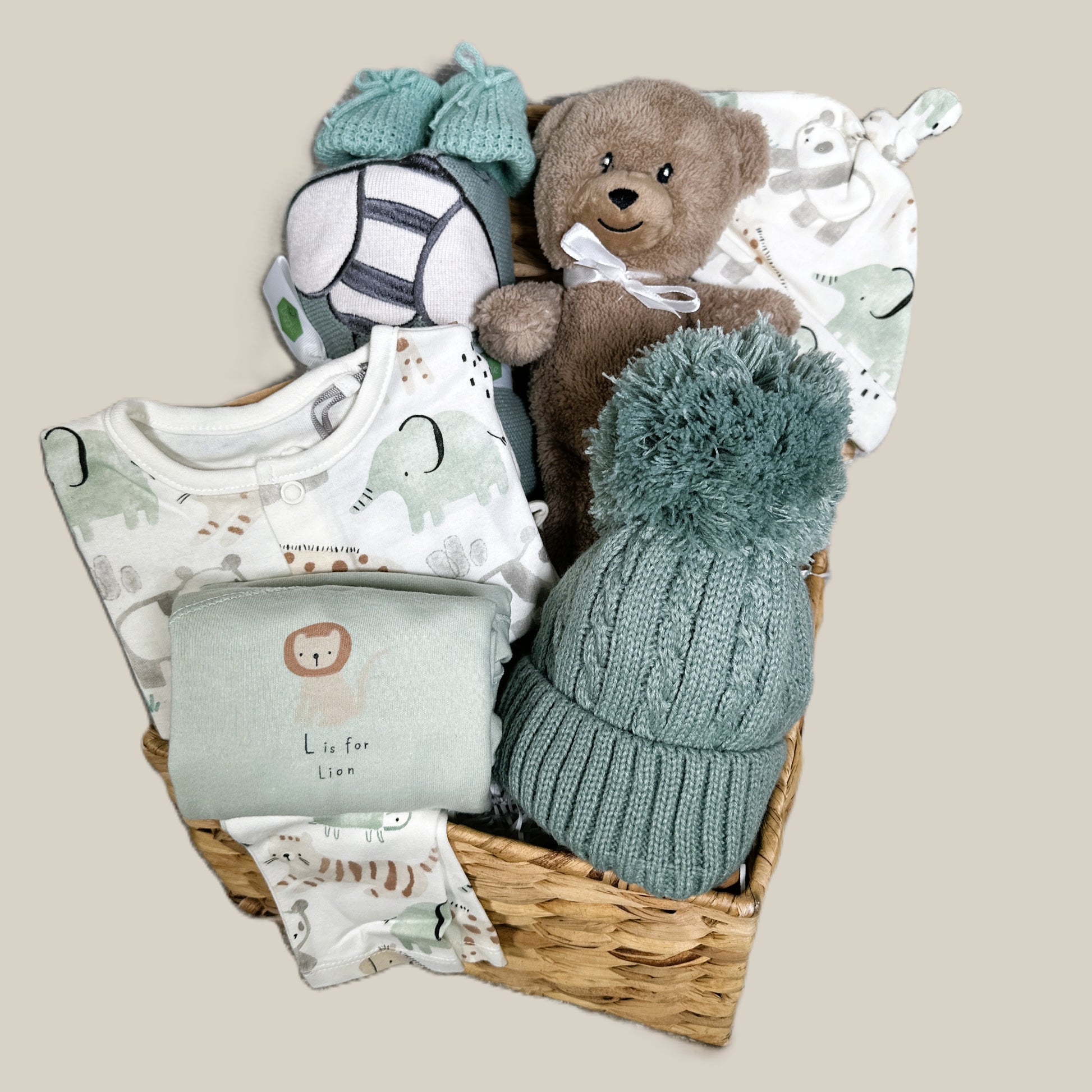 Baby gift basket with toys, clothing, and a hat on a beige background