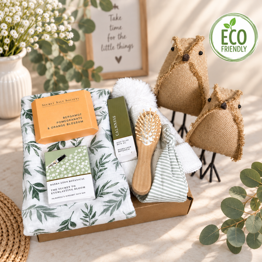 New Baby gift hamper with green leaf print swaddle, baby hairbrush, tow baby hats and some mummy treats