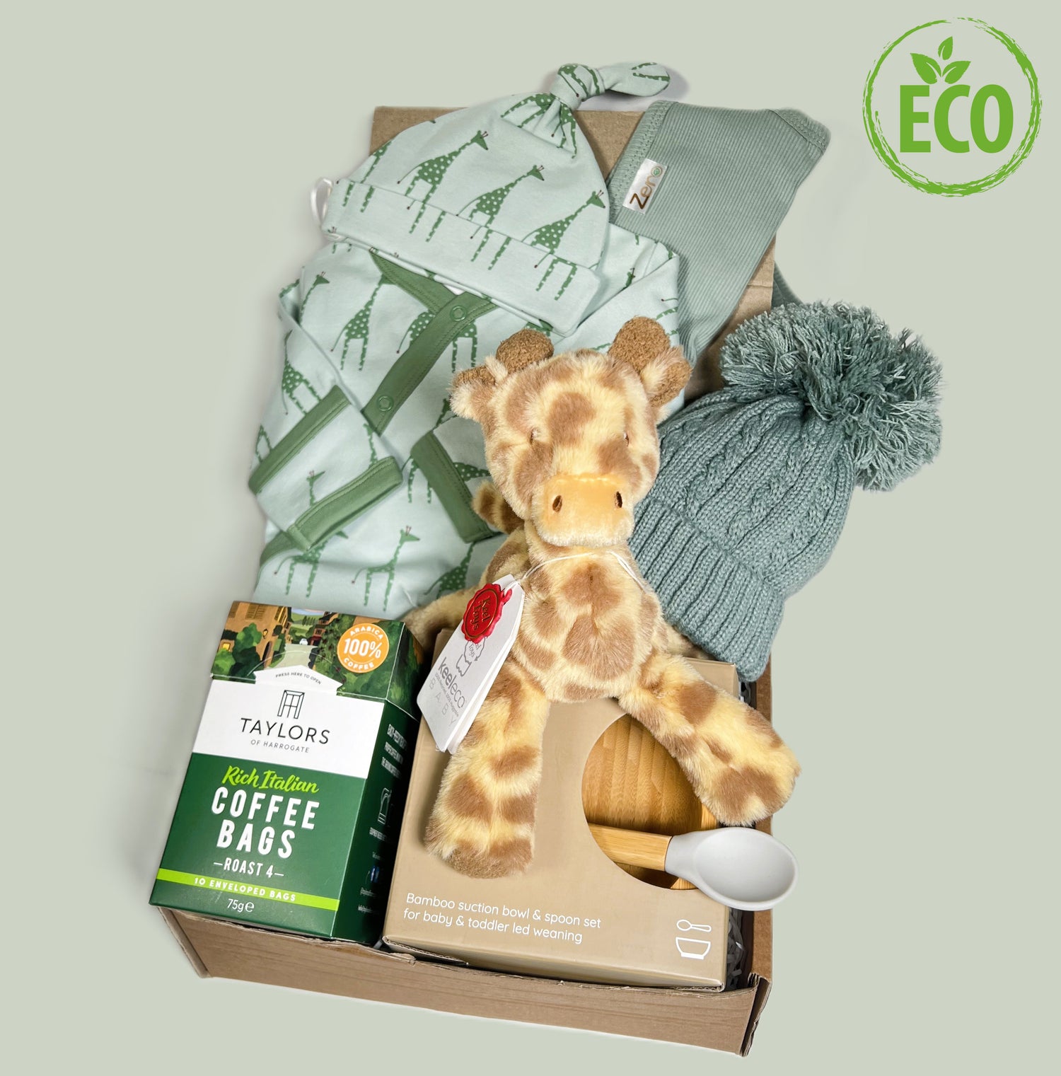 Unisex new Mummy and baby gift hamper with Green organic cotton baby skleep suit with giraffe print and matching bay knot hat, a baby soft toy giraffe, a bamboo baby bowl and spoon weaning set and a green baby pompom hat.