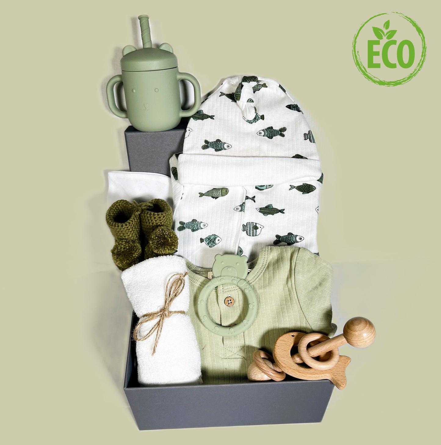 Neutral new mummy hamper box including a crocodile print baby layette set, a silicone baby cup and matching teddy teething ring, a montessori baby rattle, a pair of crcochted baby bootees and a baby keepsake box.