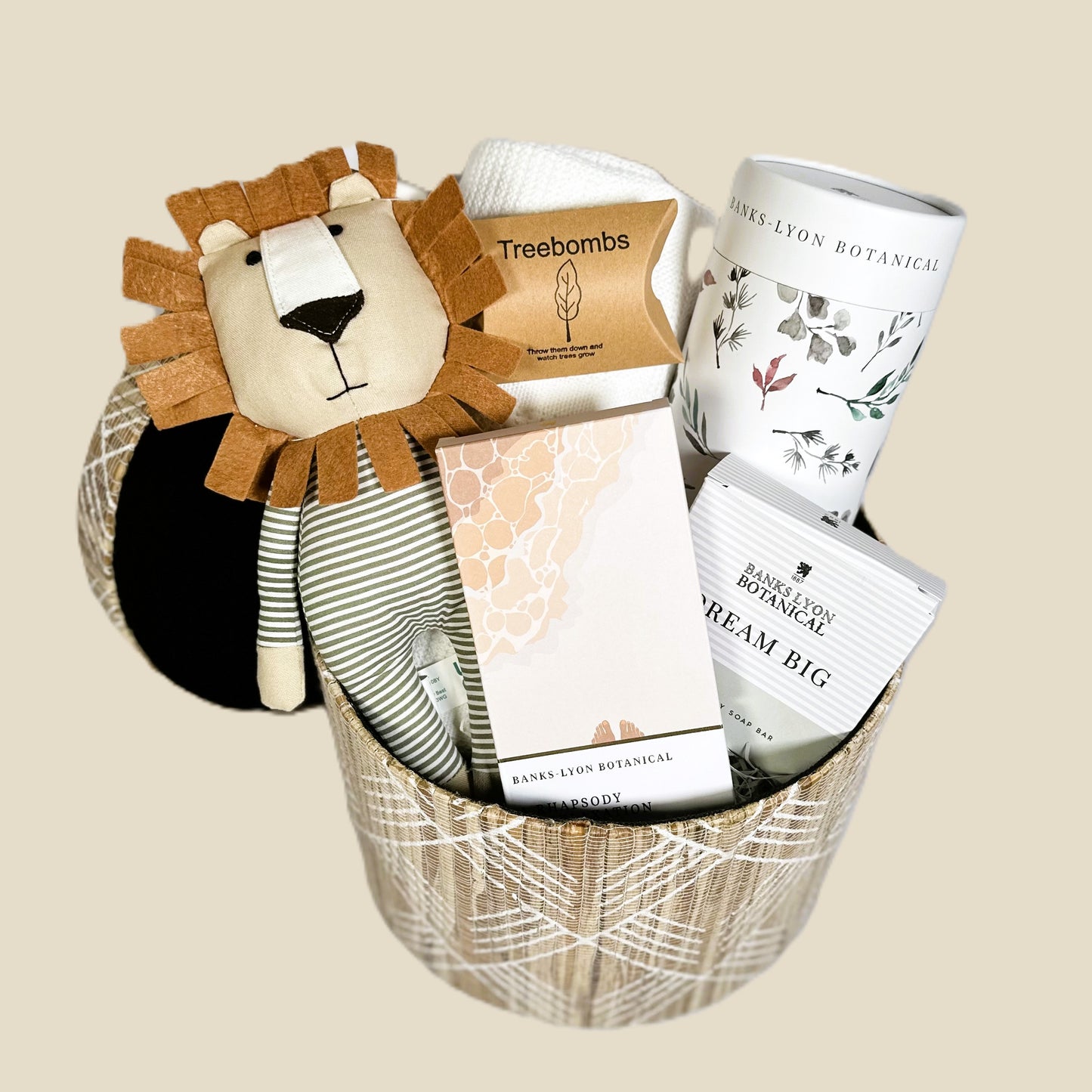 A new baby hamper in a seagrass storage box with a Caron the lion soft baby toy, a white cotton cellular baby blanket, a large bamboo baby swaddle blanket/muslin, a bar of organic baby soap , a solid oil bath soap bar and 3 Treeombs.