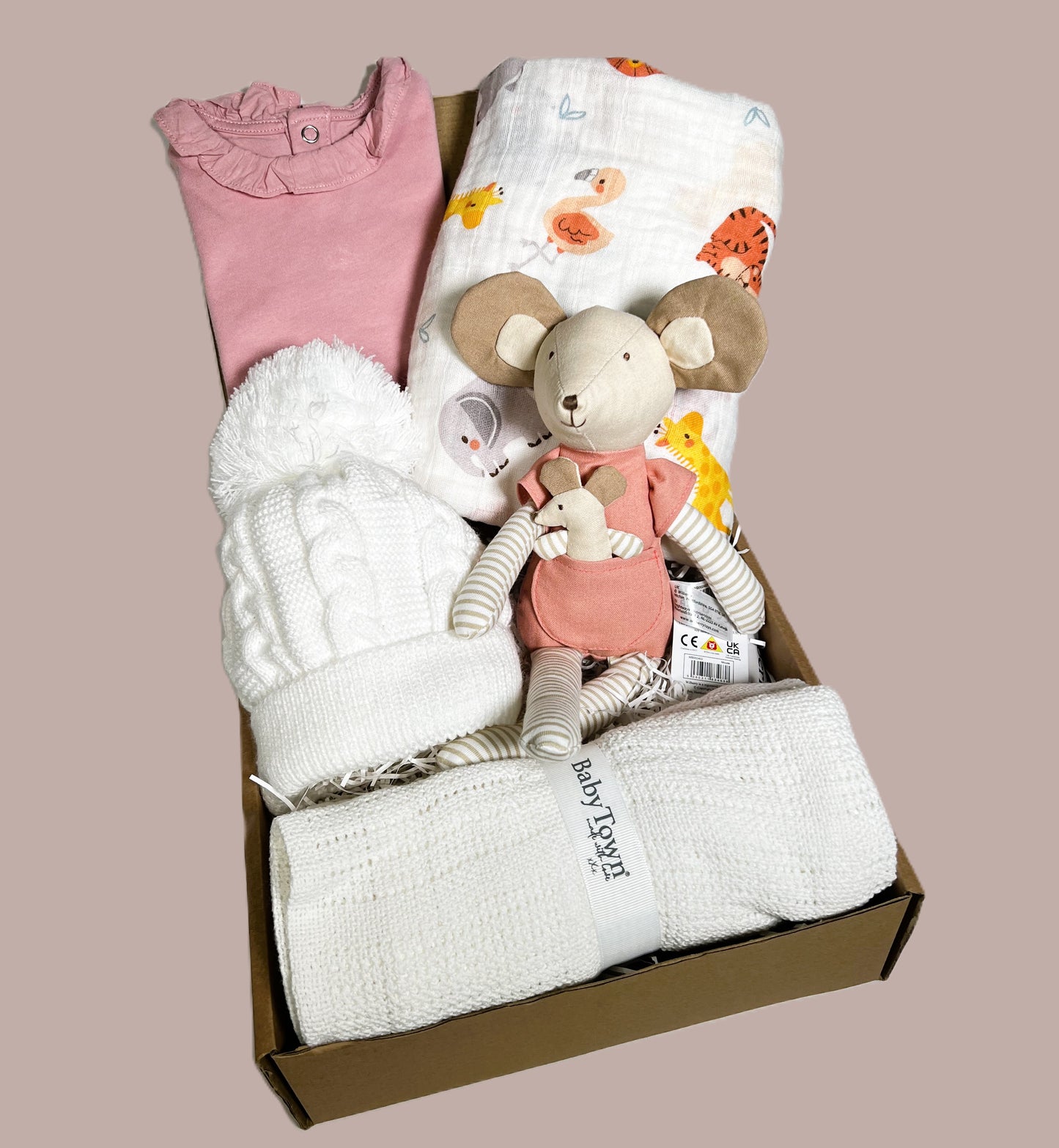 A lovely new baby girl gift containing a white cellular baby balnket, a white baby pompom hat, a large baby swaddle blanket, a Wilberry Families mouse soft baby toy , a pink baby bodysuit and three Treebombs.