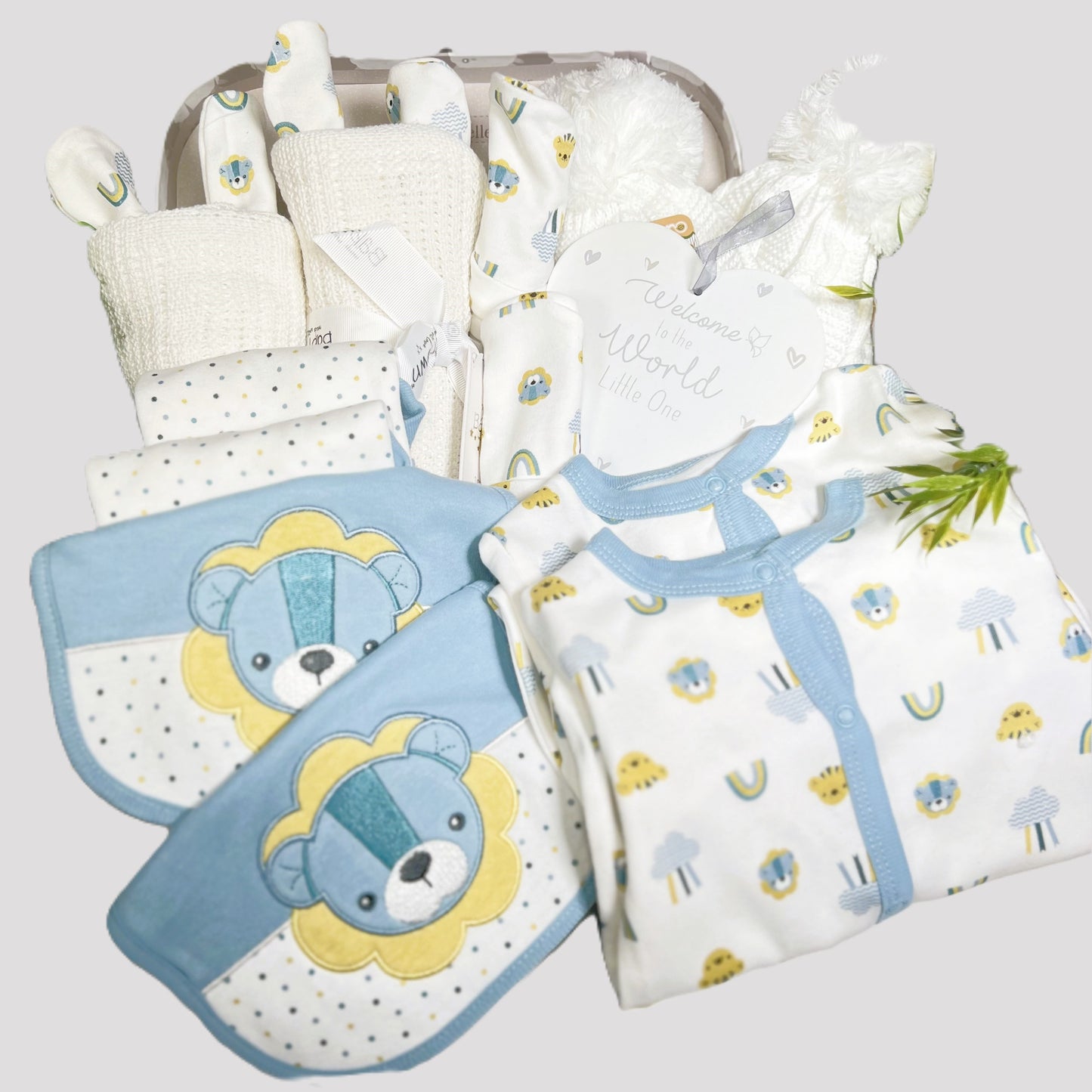 New twins baby boy hamper with lion sleeps suits in blue and yellow with matching baby bodysuits bibs, baby hats and scratch mits plus 2 white cotton cellular baby blankets, 2 white baby pompom hats and a white and grey nursery plaque.