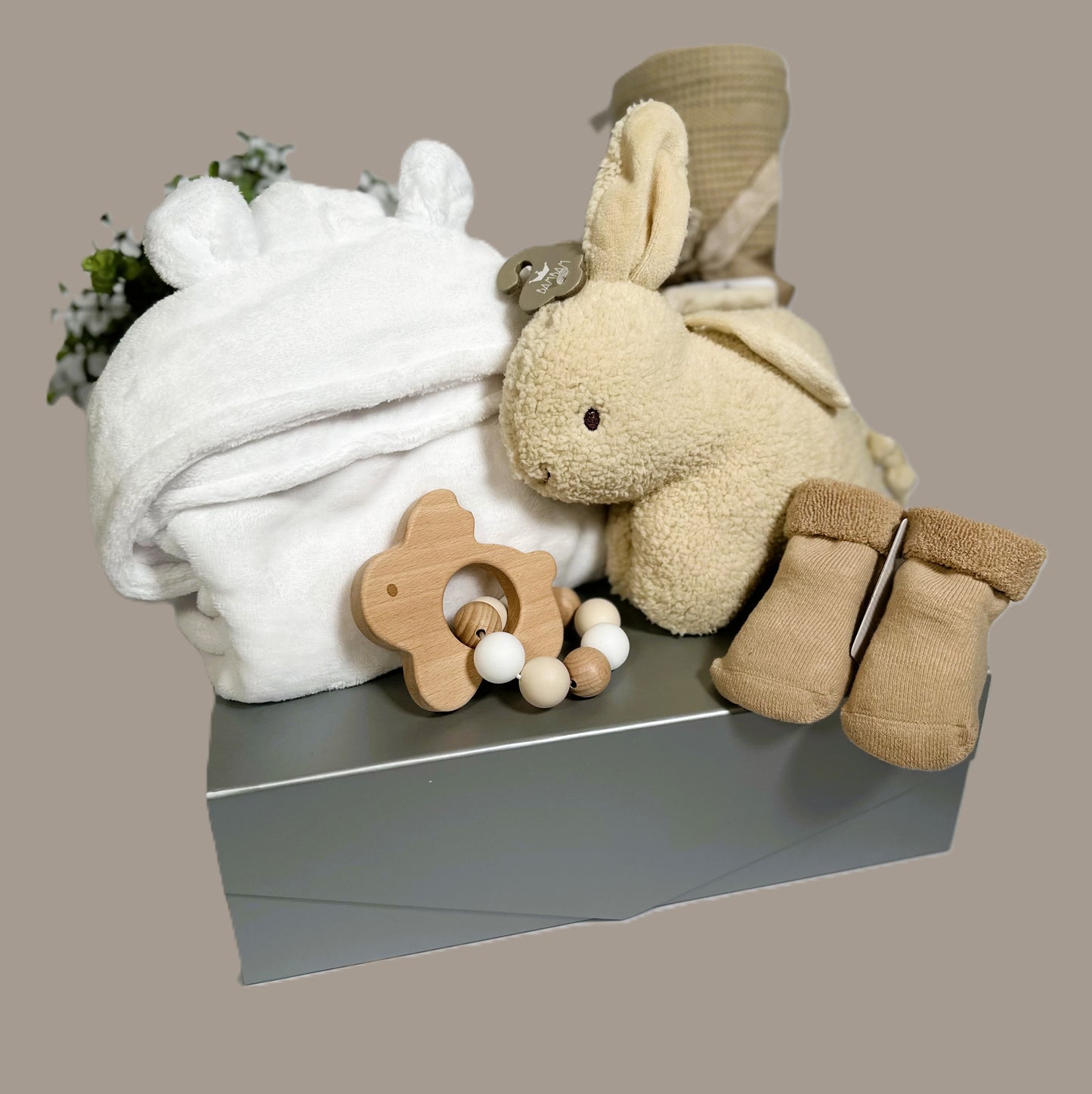 A Beautiful new baby hamper with a Bambam musical Bunny, a pair of baby socks, a baby dressing gown, cellular baby blanket and a bunny wood and  a silicone teething ring.