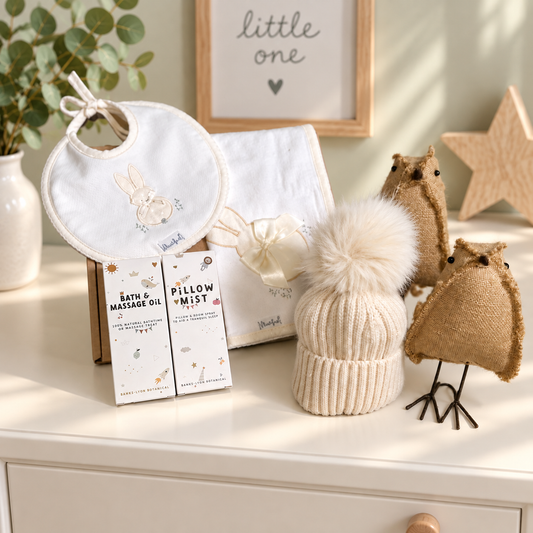 Baby gift hamper with hat, bib, baby pillow mist and baby massage oil on a light green background