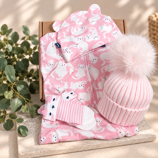 Baby girl hamper gift with pink zip up romper with a white kitty print and two baby hats.